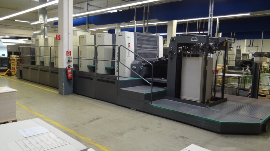 Große industrielle Druckmaschine in einer Fabrikhalle.