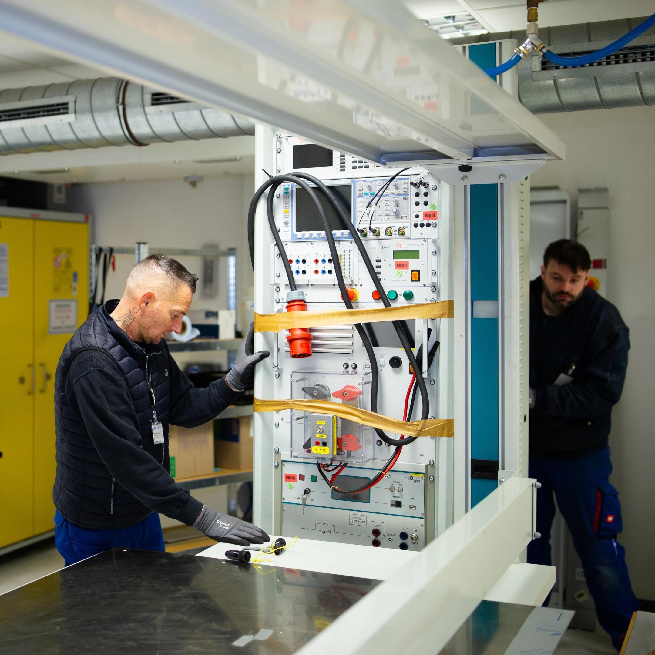 Zwei Männer arbeiten an einem technischen Gerät in einem Labor oder Werkstatt für einen Laborumzug.