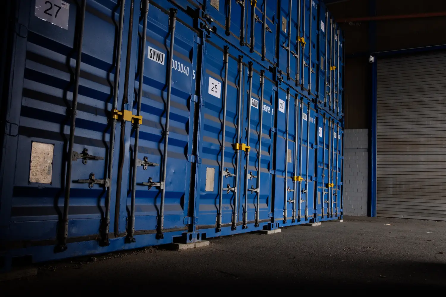 Reihe blauer Lagercontainer in einem dunklen Lagerraum.