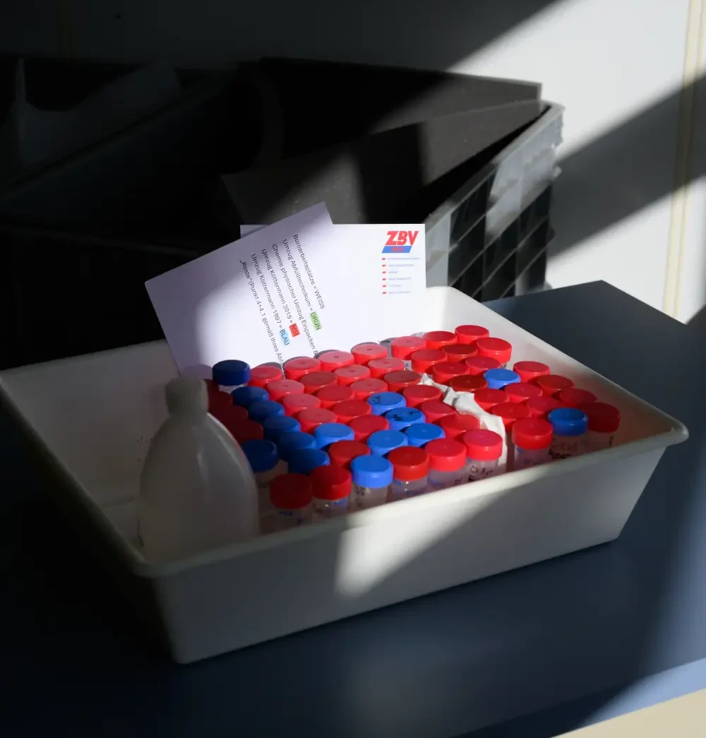 Tablett mit mehreren kleinen Fläschchen mit roten und blauen Deckeln und einem Zettel darauf.